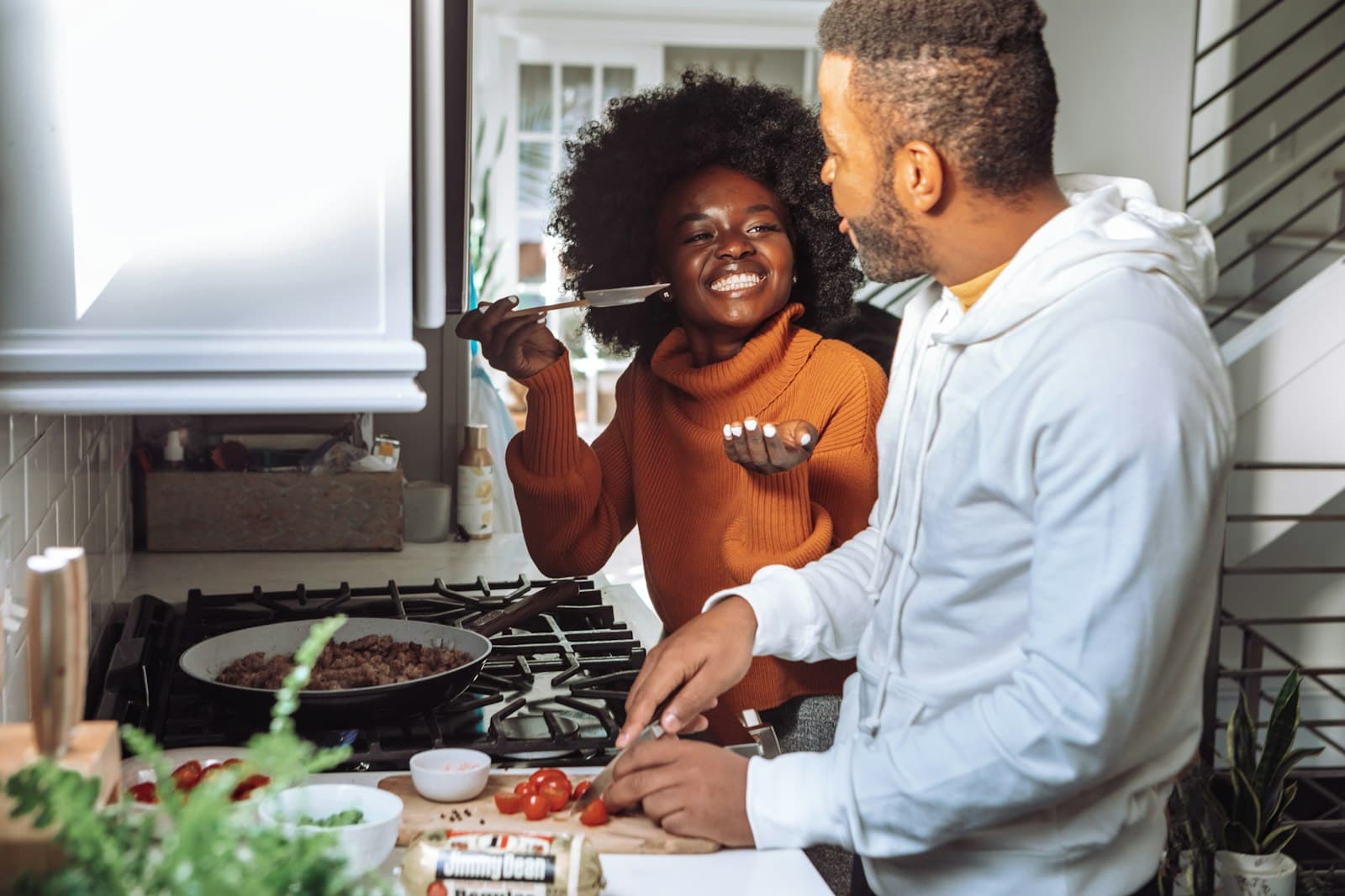 A couple cooking together at the stove.